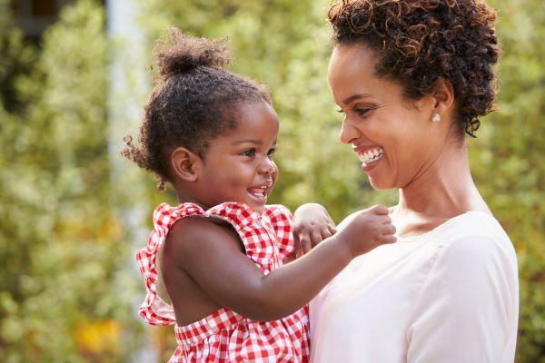 mother carrying and smiling with daughter