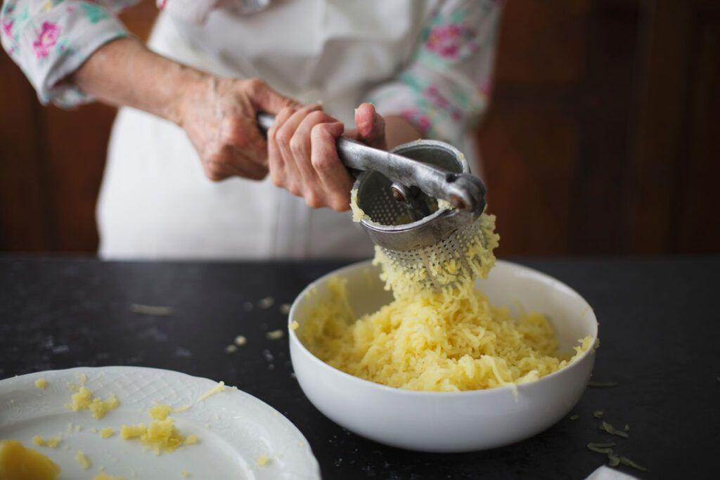 A person preparing a bland diet for gastritis by mashing potatoes