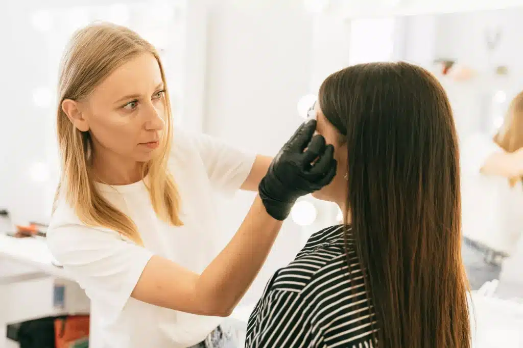 A dermatologist checking a patient's skin around her face.